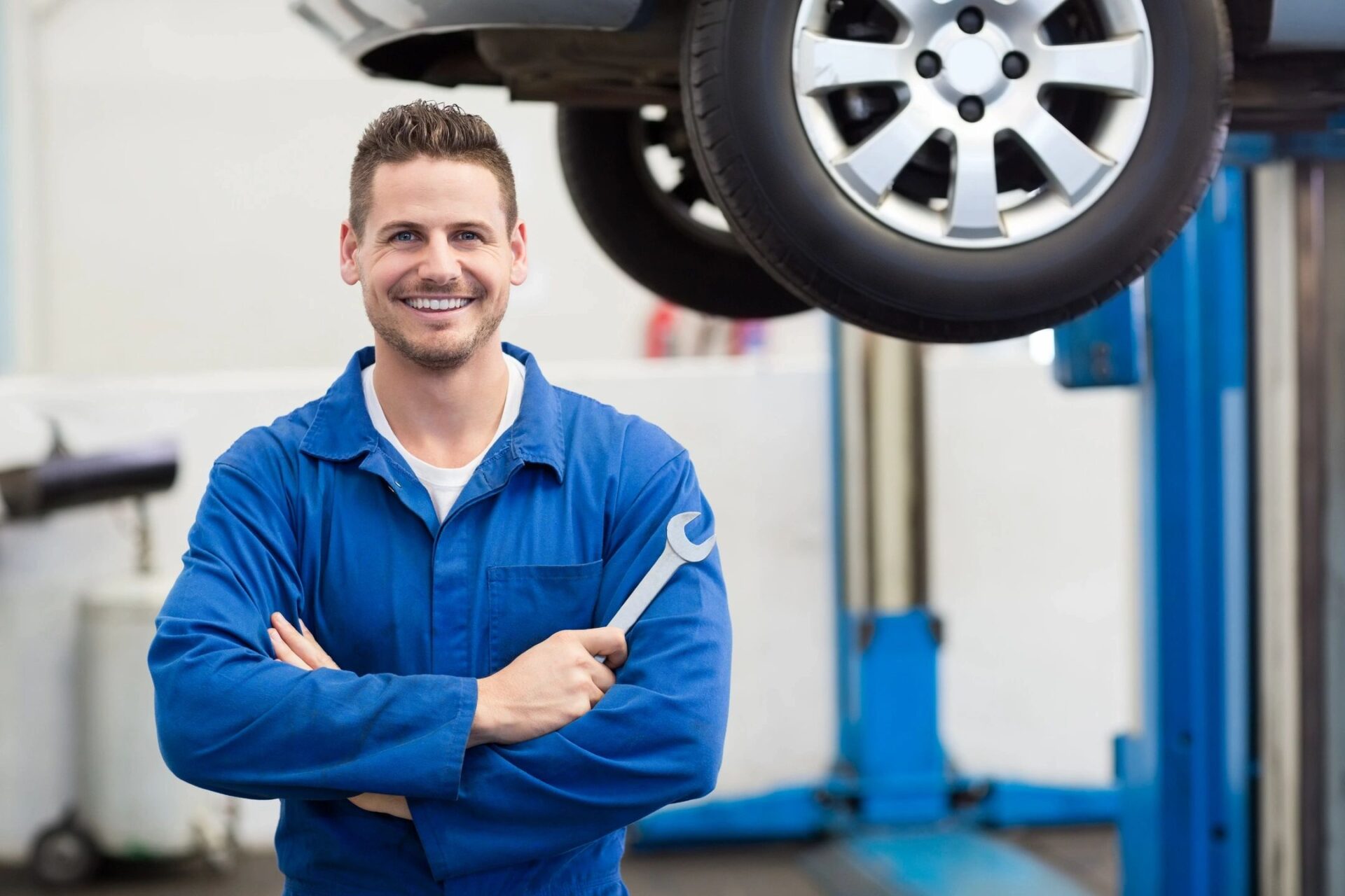 A man in blue shirt holding wrench near tire.