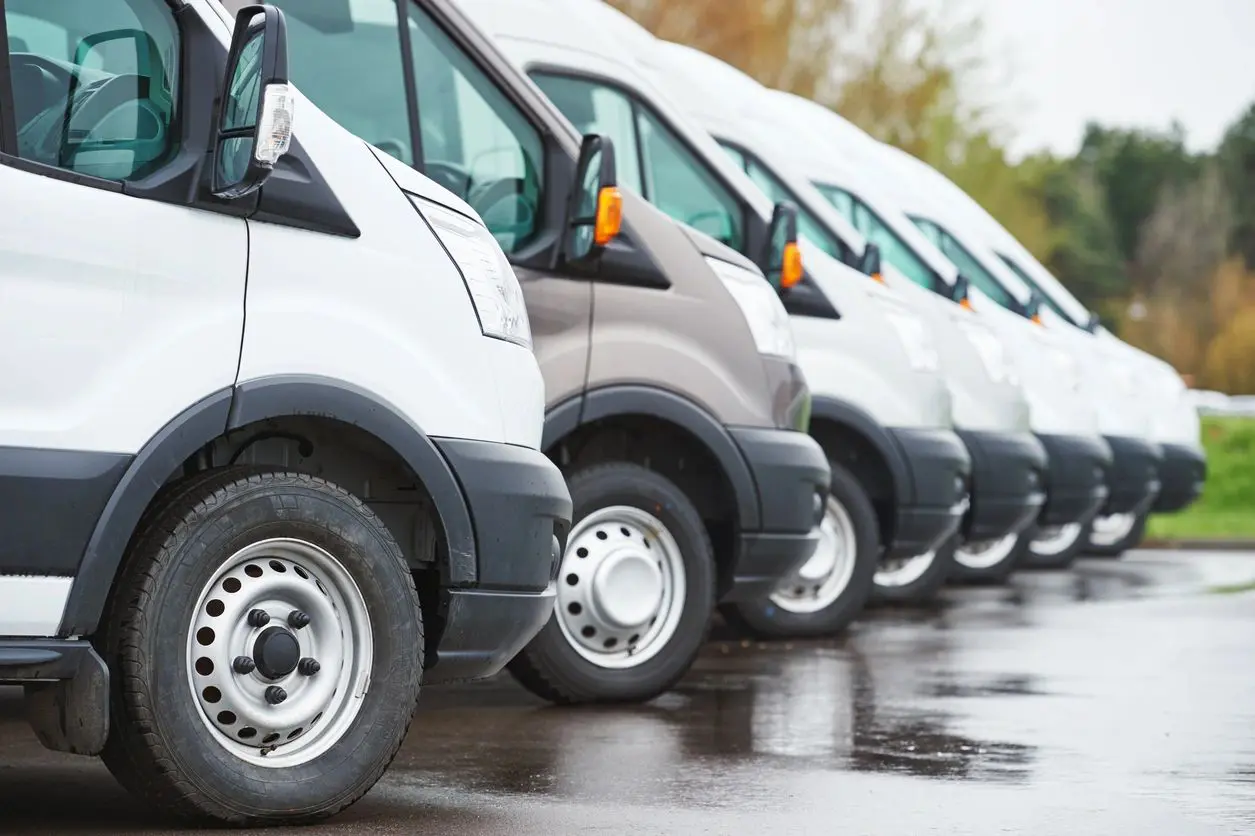 A line of white vans parked in a row.