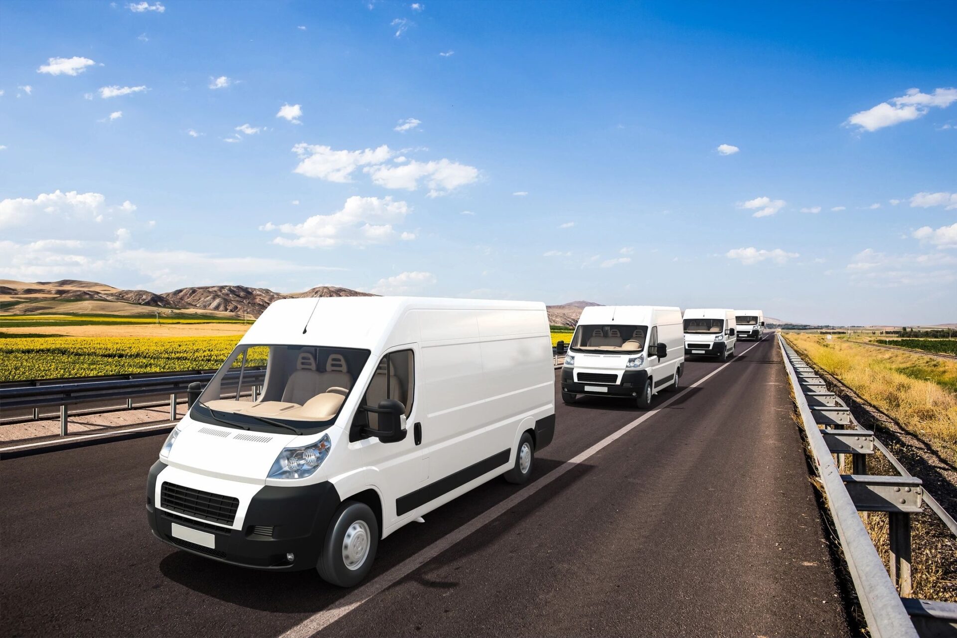 A line of white vans driving down the road.