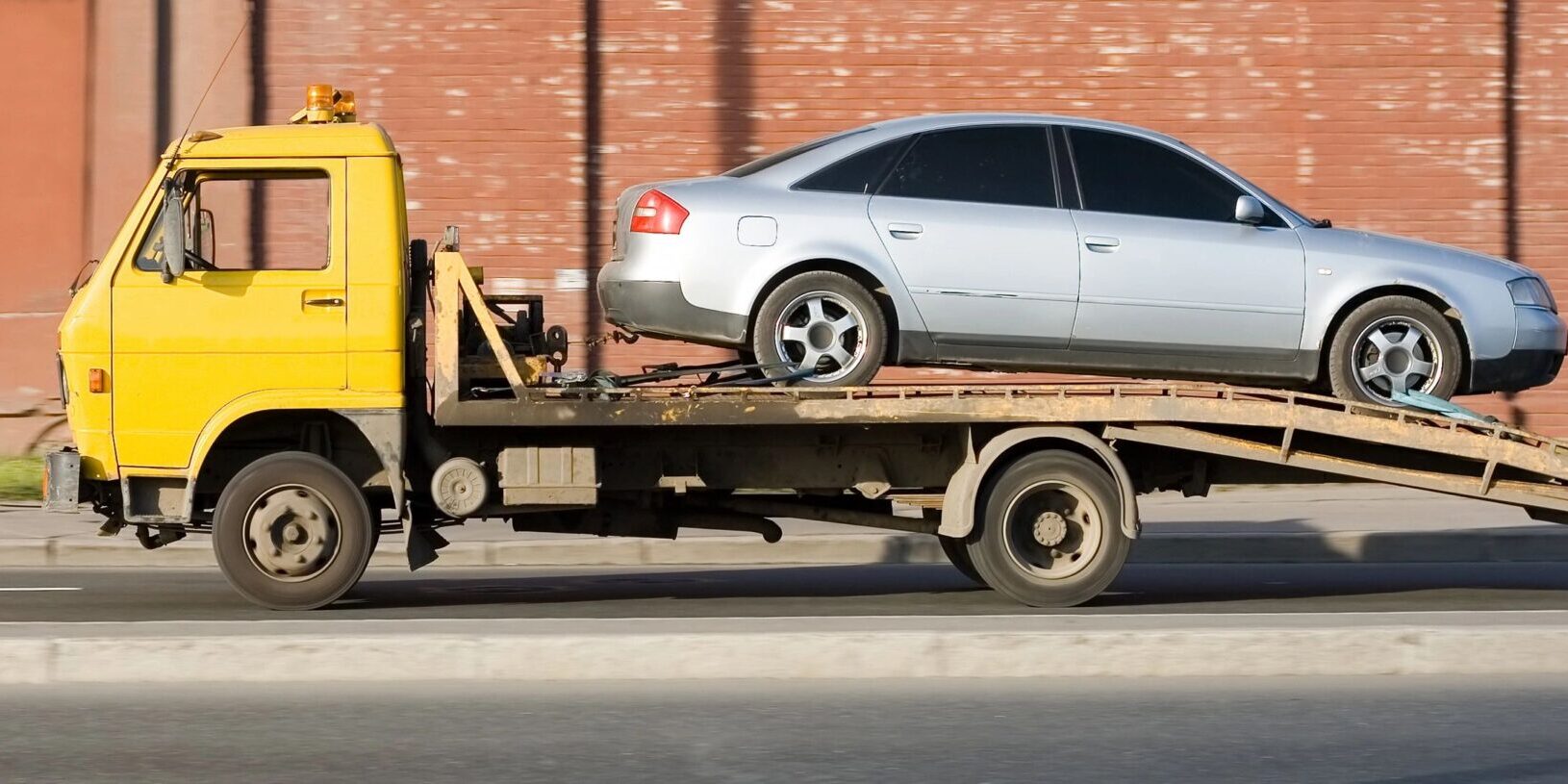 A car is being towed on the back of a truck.